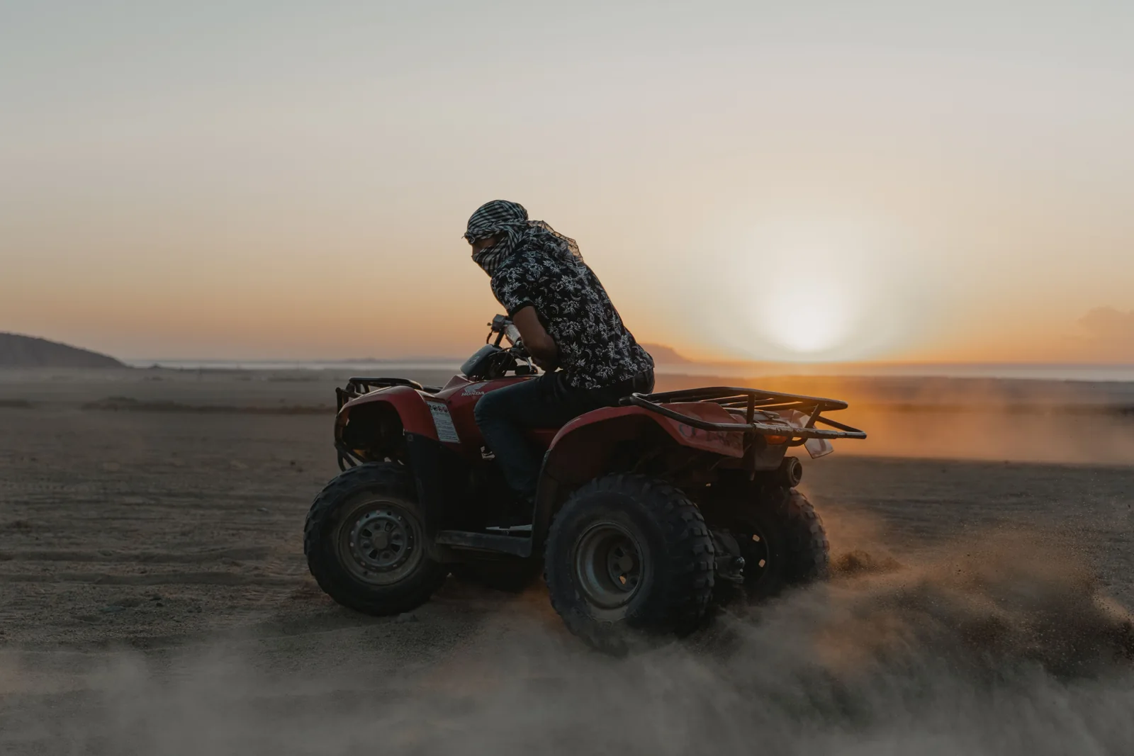 Quad bike rider crossing the desert at sunset near Marrakech