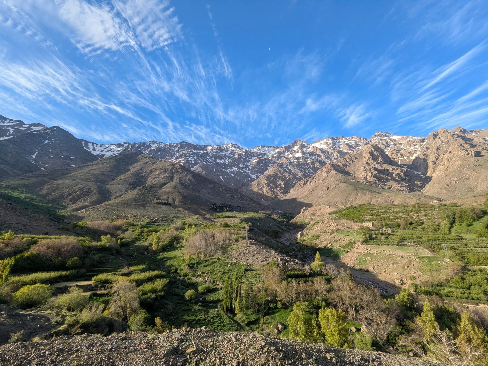 Green valley beneath rocky, snow-dusted Atlas Mountains near Imlil and Asni