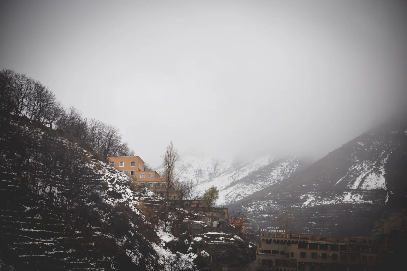 Village buildings and terraced hillsides covered in snow and mist in the Atlas Mountains