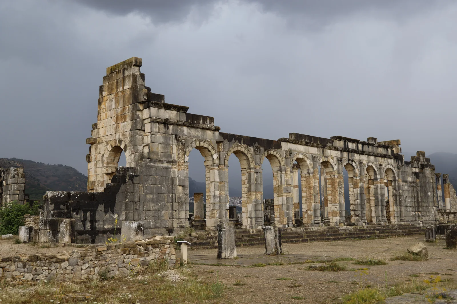 Ancient stone columns and arches beneath a cloudy sky in Morocco